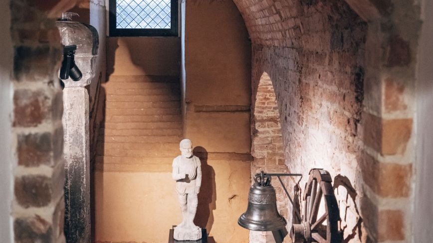 Figurka kata poznańskiego, dzwon i koło na wystawie w podziemiach ratusza.