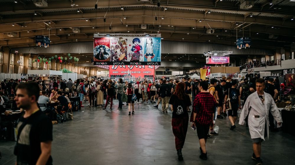 Tłumy ludzi spacerujących po hali targowej MTP. Nad tłumem wielkie plakaty z wizerunkami anime.