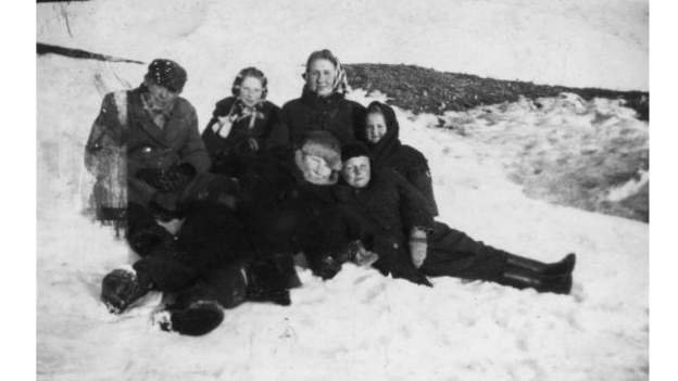 Biała okładka książki z czarno-białym zdjęciem grupy siedzącej na śniegu.