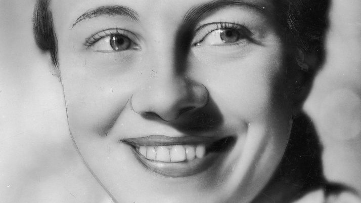 Czarno-biały portret uśmiechniętej młodej kobiety.